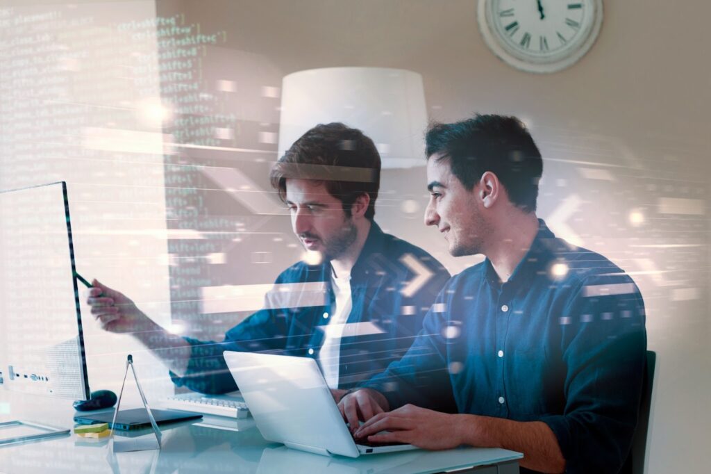 Two men working on computer with coding