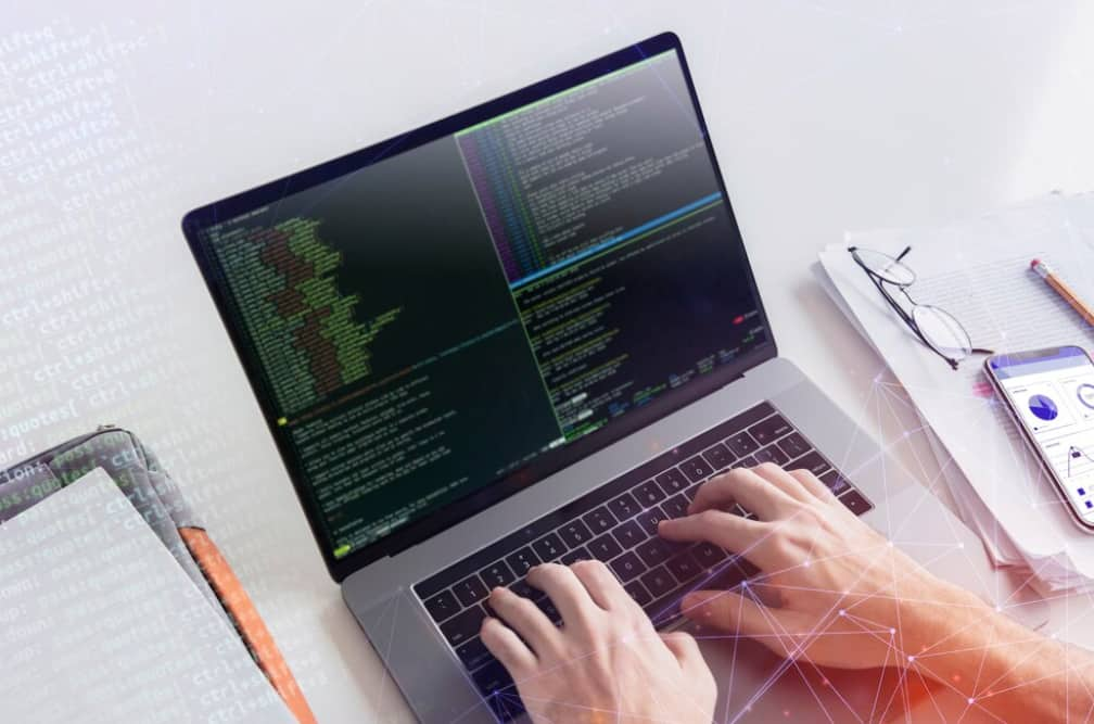 Overhead view of a person coding on a laptop with digital graphics