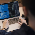 A man writes code on a laptop