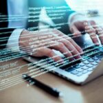 A man writes computer code on a laptop